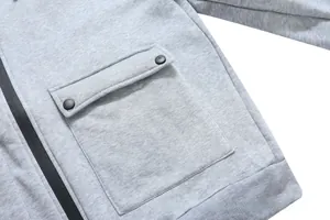 Detail of light gray hoodie showing cargo pockets with black snaps and side zipper closure