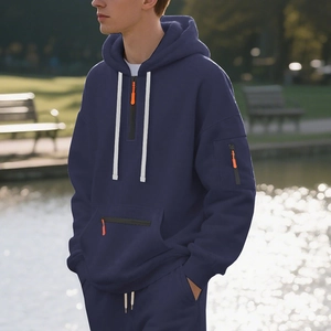 Detail of navy hoodie with white drawstrings and orange zipper pockets on a man
