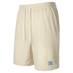 Detail of beige corduroy shorts featuring elastic waistband, drawstring and sports patch