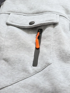 Détail de veste en tricot gris avec poche à bouton pression noir et tirette orange