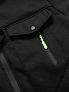 Détail de veste noire avec fermeture éclair vert néon et poche à rabat boutonnée
