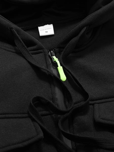 Gros plan d'un sweat à capuche noir avec tirette vert fluo et maille épaisse de qualité