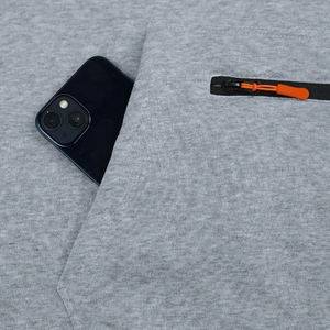 Détail du pantalon en maille grise avec poche à fermeture éclair orange et espace téléphone