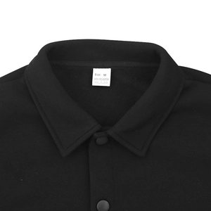 Détail du col de veste tactique noire montrant l'étiquette 100% polyester et boutons