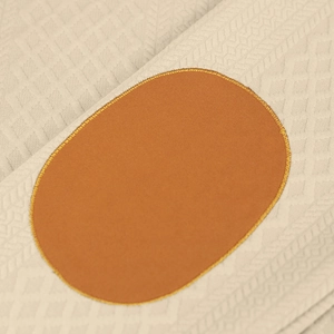 Nahaufnahme von beigem Jacquard-Strickstoff mit braunem Ellenbogen-Patch und gelber Naht