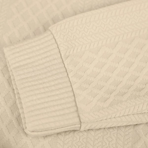 Nahaufnahme der beigefarbenen Strickbündchen mit Rautenmuster und geripptem Ärmeldetail