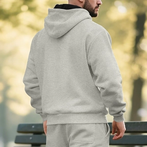 Back view of a men's light grey fleece hoodie and jogger set in a park setting