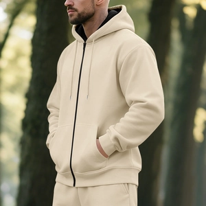 Detail view of cream zip-up hoodie featuring black zipper, side pockets, and ribbed cuffs