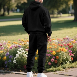 Rear view of black fleece tracksuit set including a hoodie and joggers in a park