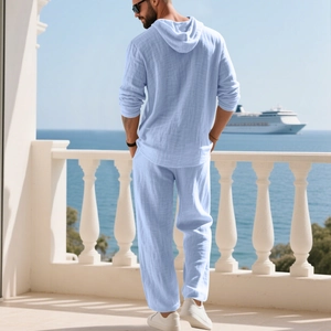 Men's light blue linen set featuring a hooded shirt and trousers against a sea background