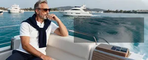 Men's summer knit polo shirt in white with navy sweater on a luxury yacht