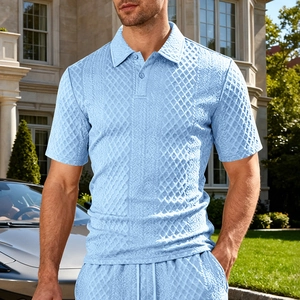 Dettaglio polo in maglia celeste con trama a griglia e motivi a treccia in primo piano