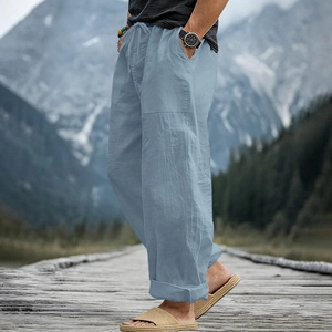 Detail of light blue linen trousers showing drawstring waist and cargo pockets outdoors