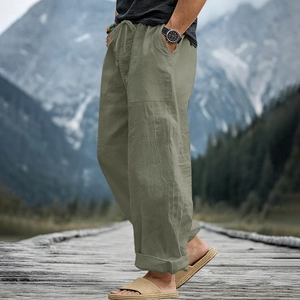 Detail of grey-green men's linen pants with drawstring waist on outdoor wooden path