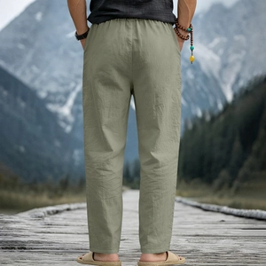 Men's sage green linen pants featuring a relaxed fit and elastic waist in a scenic view
