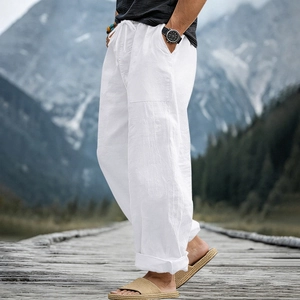 Close-up of white linen blend trousers with drawstring waist on a scenic mountain path