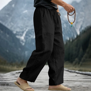 Detail view of black linen pants featuring breathable texture and elastic waist on a model