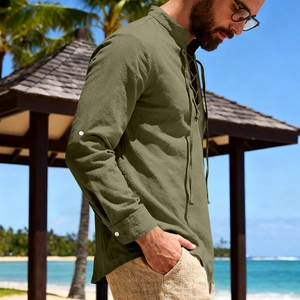 Detail of olive green linen Henley shirt with lace-up collar and adjustable cuffs on beach