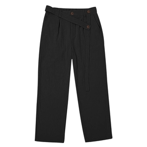Detail view of black linen trousers featuring asymmetric buttons and adjustable drawstring waist