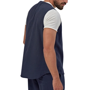 Dettaglio del gilet blu scuro con trama in lino e orlo curvo indossato dal modello