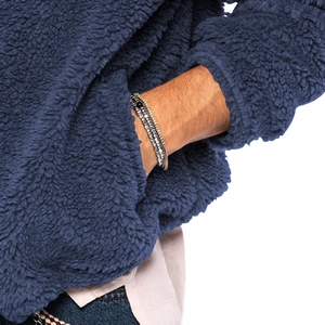 Detail eines mehrlagigen Perlenarmbands mit Metallakzenten und einer blauen Fleecejacke
