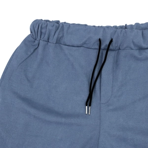 Dettaglio dei jogger blu con vita elastica, coulisse nera e punte in metallo
