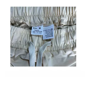 Detail of beige athletic shorts featuring elastic drawstring waistband and 100% polyester label