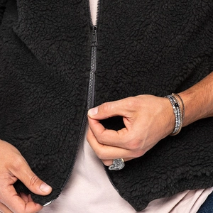 Detailansicht der schwarzen Fleece-Textur und des hochwertigen Metallreißverschlusses der Jacke