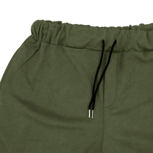 Dettaglio dei pantaloni casual verde militare con vita elastica e coulisse nere con punte in metallo