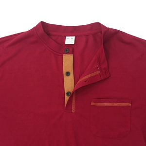 Détail du polo bordeaux avec patte à trois boutons et couture jaune sur la poche poitrine