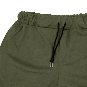 Detailed view of elastic waistband with black drawstring on olive green suede trousers