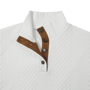 Detalle de suéter de punto blanco con patrón texturizado, tapeta de gamuza marrón y botones metálicos
