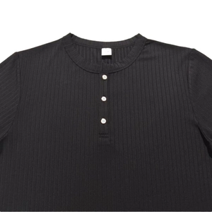 Detail eines schwarzen Henley-Shirts aus Rippstrick mit drei weißen Knöpfen und Struktur