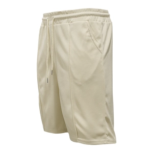 Dettaglio dei pantaloncini in maglia a nido d'ape crema con coulisse elastica e tasche