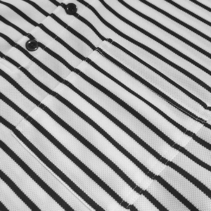 Macro view of men's striped cotton shirt showing black button and chest pocket detail