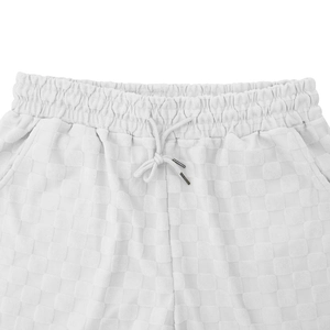 Macro detail of white shorts with checkerboard texture, elastic waist and metal-tipped drawstring