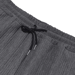 Detalle de pantalón de pana gris oscuro con cintura elástica y cordones con puntas metálicas