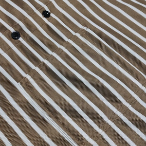 Detailed macro view of khaki striped piqué cotton fabric and premium black buttons on shirt
