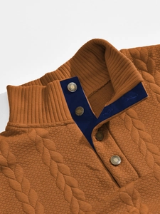 Primo piano del maglione in maglia jacquard marrone caramello con texture e bottoni in metallo