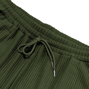 Detalle de pantalón de pana verde oscuro con cintura elástica y cordón con puntas de metal