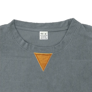 Detail of grey corduroy sweatshirt showing neckline texture, orange patch, and size M label