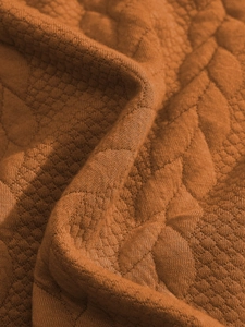 Dettaglio macro del tessuto jacquard lavorato a maglia arancione con trapuntatura