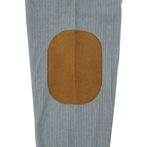 Macro detail of blue corduroy fabric featuring a brown oval reinforced elbow patch