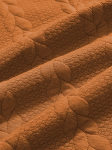Dettaglio macro del tessuto jacquard trapuntato arancione con motivo a trama a rombi
