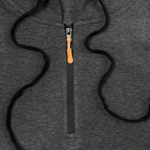 Detail of half-zip pullover hoodie with orange zipper pull and black drawstring