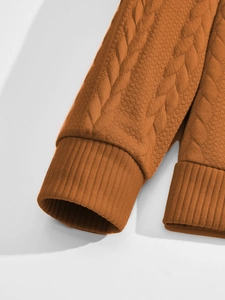 Dettaglio ravvicinato della manica in maglia jacquard arancione con polsino a coste