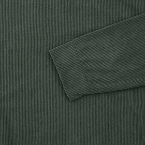 Close-up of dark green corduroy fabric showing ribbed texture and elastic cuff detail