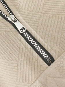 Vista macro de tela de punto jacquard beige con cremallera metálica de alta calidad