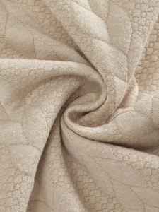 Vista macro detallada del tejido de punto jacquard beige con diseño acolchado hexagonal