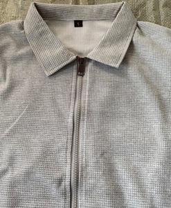 Detail of light grey waffle texture polo jacket with a sturdy metal zipper and collar